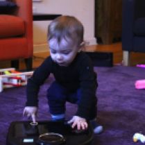 Toddler plays robot vacuum