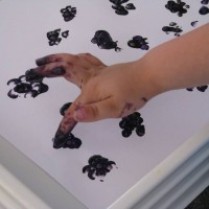 A child make blackberry finger painting